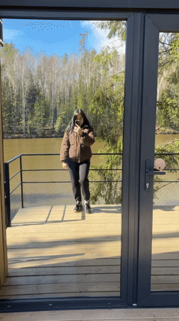 Woman takes selfie near glass door in Mishkino
