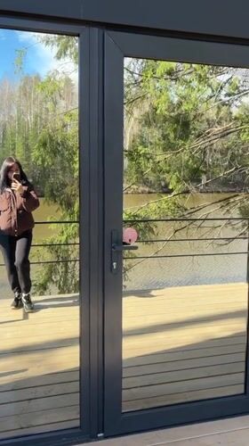 Woman takes selfie near glass door in Mishkino
