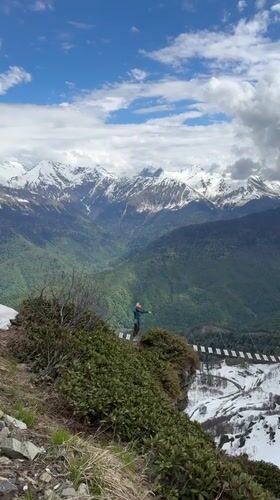 Man gestures from cliff platform near suspension bridge in Russia