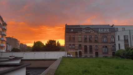 Dramatic sunset illuminates Mechelen skyline with orange hues