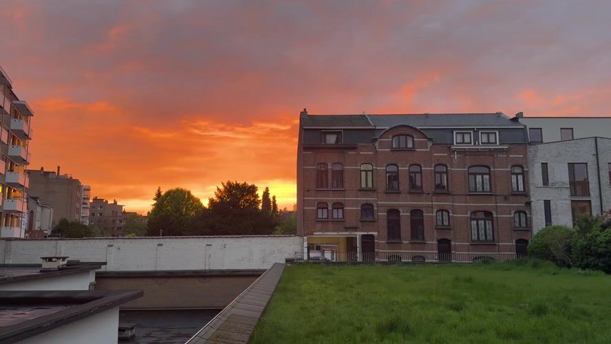 Dramatic sunset illuminates Mechelen skyline with orange hues