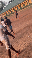 Young men play informal football on dirt field in Nigeria