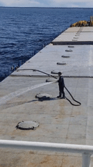 Crew member cleans ship deck near Russian coast