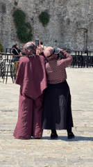 Women socialize at sunny Budva marina waterfront