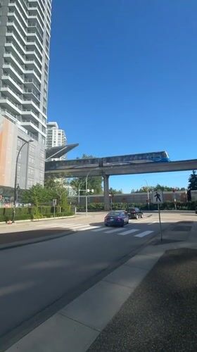 Blue train crosses elevated tracks over New Westminster street