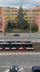 Prague street traffic: trams, cars, and scooters on a gray afternoon