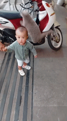 Toddler and adult share quiet moment on Da Lat sidewalk