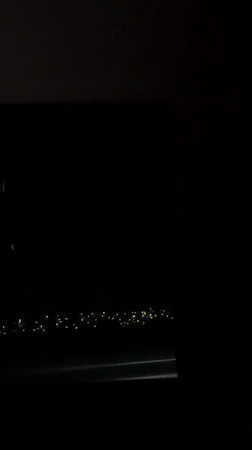 Nighttime aerial view shows city lights from airplane window