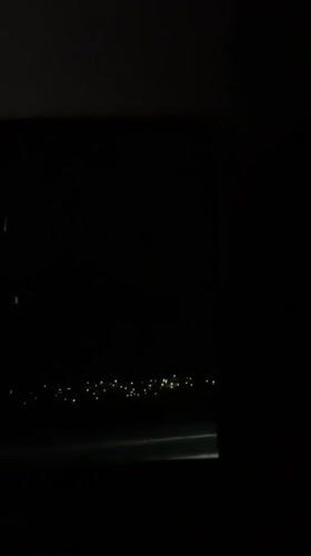 Nighttime aerial view shows city lights from airplane window