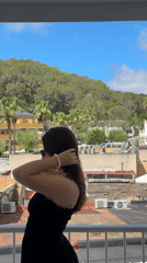 Woman poses on balcony overlooking Calvià, Spain coastline
