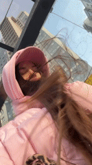 Woman films windy selfies in pink jacket, Saint Petersburg