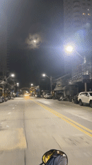 Nighttime traffic flows along Pattaya Beach Road under full moon
