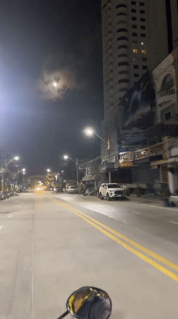 Nighttime traffic flows along Pattaya Beach Road under full moon