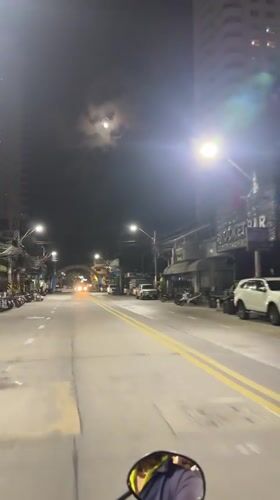 Nighttime traffic flows along Pattaya Beach Road under full moon