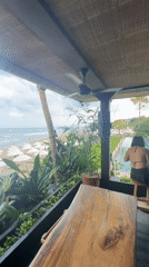 Women at beachfront bar overlook umbrella-lined North Kuta beach
