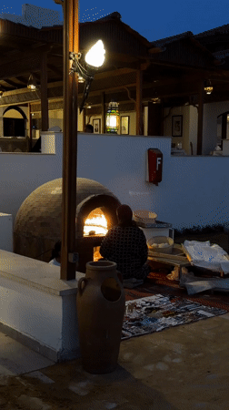 Woman tends outdoor brick oven in Sharm El Sheikh