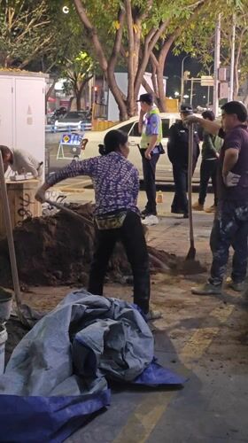 Woman shovels dirt on sidewalk in Yuzhong District