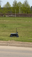 Black robot with antennas crosses grassy field in Riga