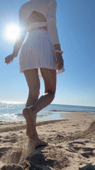 Woman in white walks toward ocean on Nesebar beach