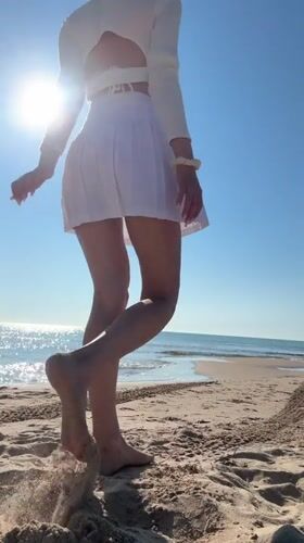 Woman in white walks toward ocean on Nesebar beach