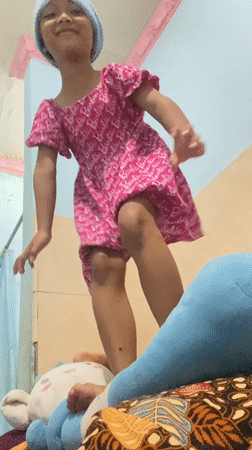 Girl in Barbie dress poses indoors in Gelam, Indonesia