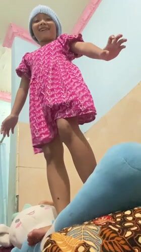 Girl in Barbie dress poses indoors in Gelam, Indonesia