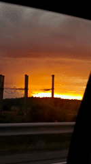 Sunset views from the road, sky blazing orange through the trees.