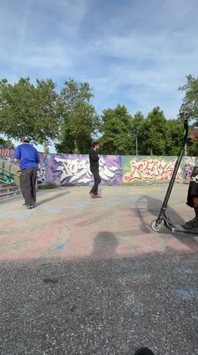 Young men perform scooter tricks, socialize at Lyon skatepark