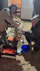 Couple grills meat outdoors in Russian village