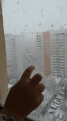Child draws on frosty window, views snowy courtyard in Khimki