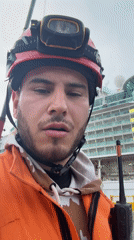 Worker with radio speaks to camera near cruise ship
