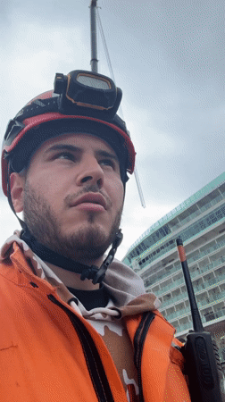 Worker with radio speaks to camera near cruise ship