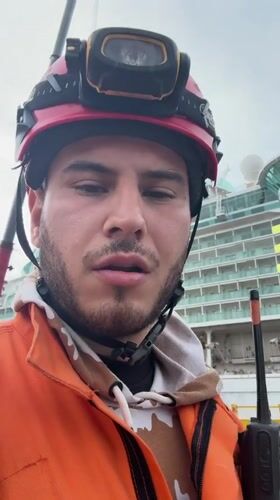 Worker with radio speaks to camera near cruise ship
