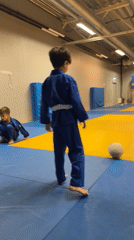 Kids training judo in a trophy-lined gymnasium