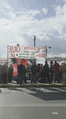 Demonstrators gather with banner in daytime Athens protest