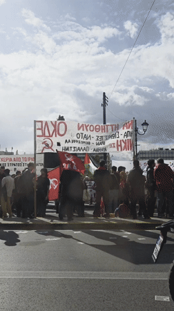 Demonstrators gather with banner in daytime Athens protest