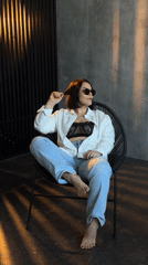 Woman in sunglasses sits in wire chair outdoors