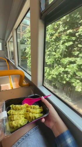 Passenger eats dumplings with pink fork on London bus