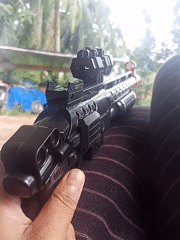 Toy rifle with scope handled outdoors in Lestari Indah