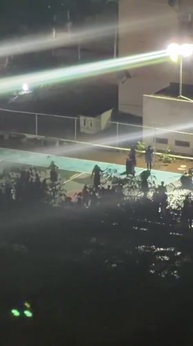 Nighttime gathering at illuminated tennis court in Ciudad Guayana