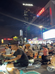 Scooter crowds gather at Futian District intersection amid city lights