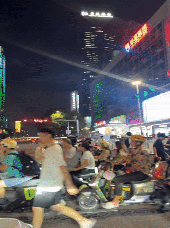 Scooter crowds gather at Futian District intersection amid city lights