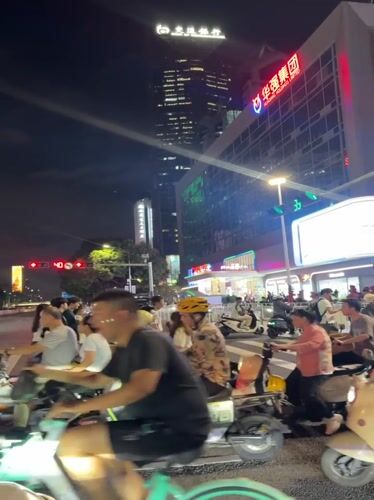 Scooter crowds gather at Futian District intersection amid city lights