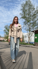 Woman in trench coat walks Perm streets amid blooming dandelions