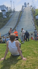 Group relaxes on grass near ski jump structure