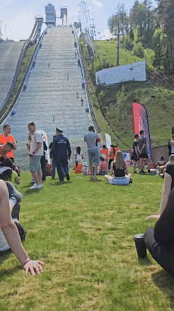 Group relaxes on grass near ski jump structure