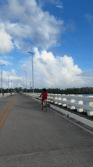 Cyclist crosses bridge under rainbow in General Luna