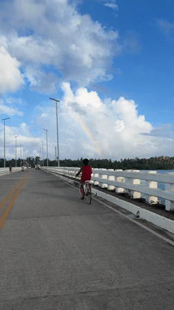 Cyclist crosses bridge under rainbow in General Luna