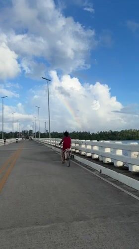 Cyclist crosses bridge under rainbow in General Luna