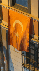 Turkish flag displayed on Beyoğlu building under artificial lighting